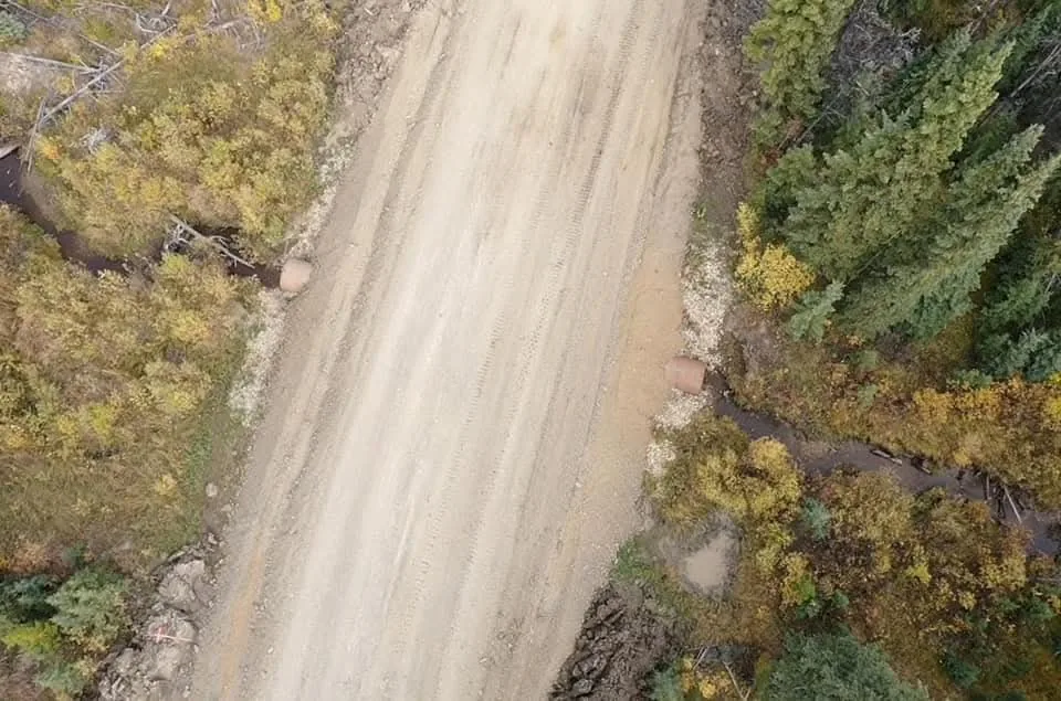 Overhead view of a gravelled access road with culverts set at a creek crossing