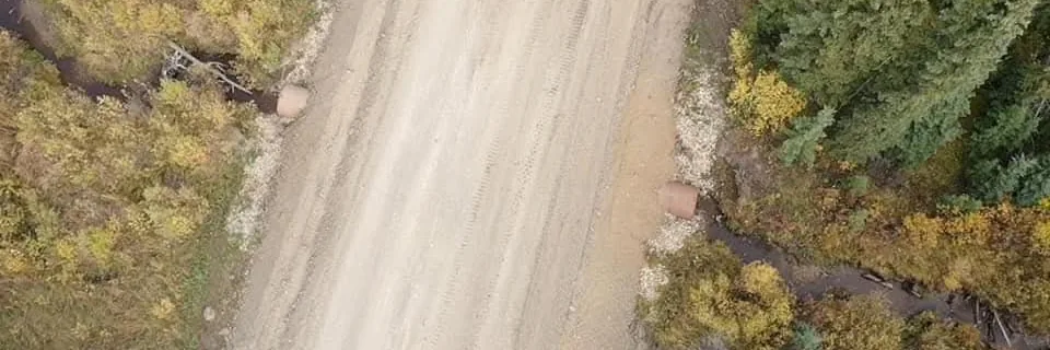 Overhead view of a gravelled access road with culverts set at a creek crossing