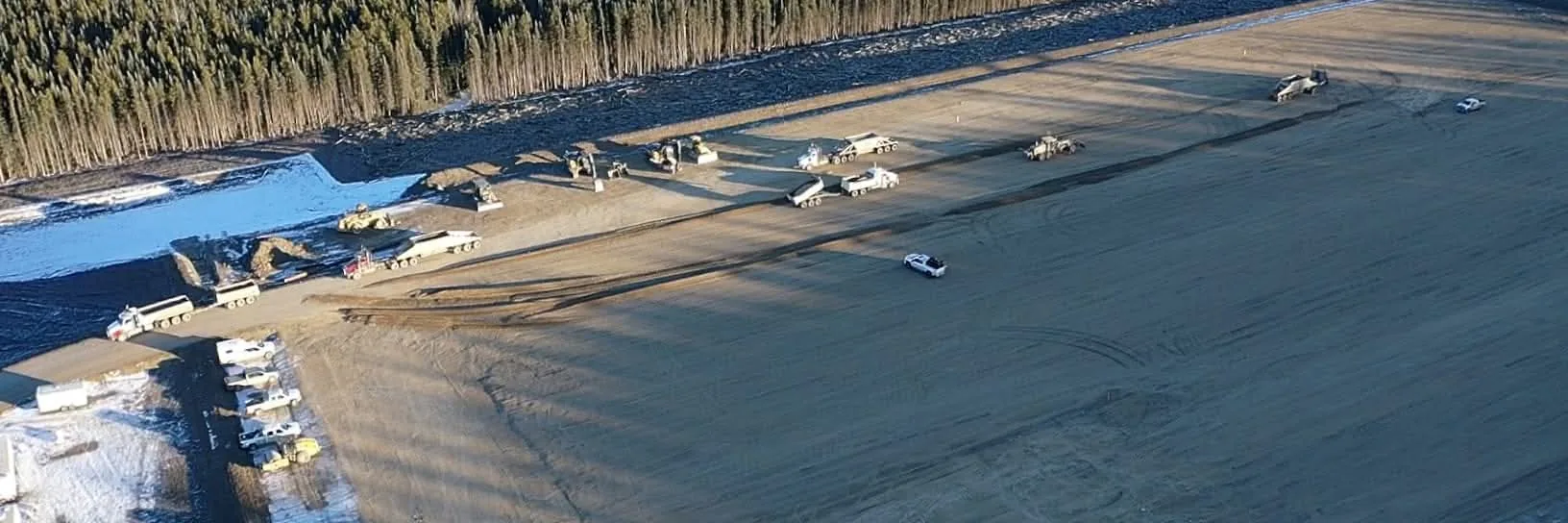 Aerial view of a large gravelled lease pad under construction with equipment working the edge