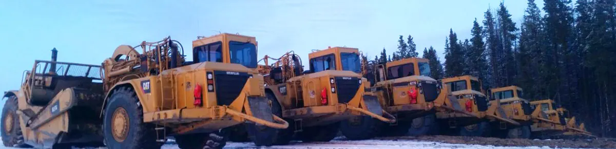 Row of scrapers parked on a snow-covered pad