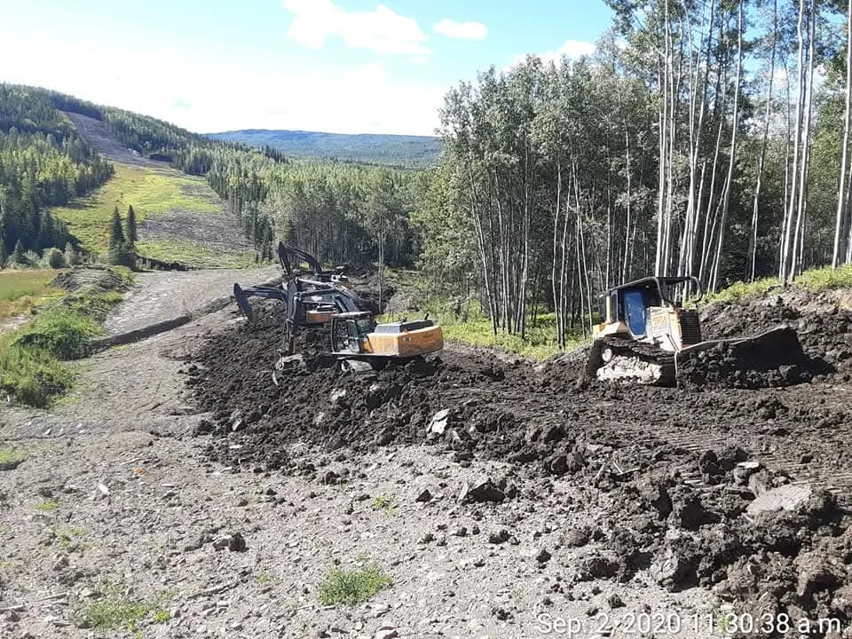 Excavators and a dozer cutting a slope on a cleared right of way