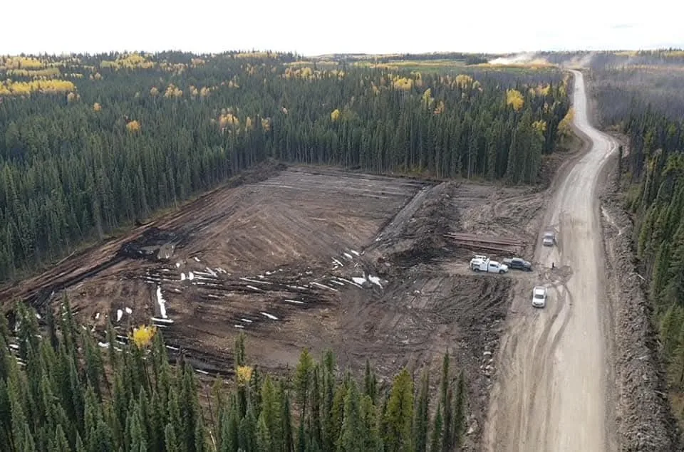 Aerial view of a cleared pad with salvaged timber decked beside a gravel access road