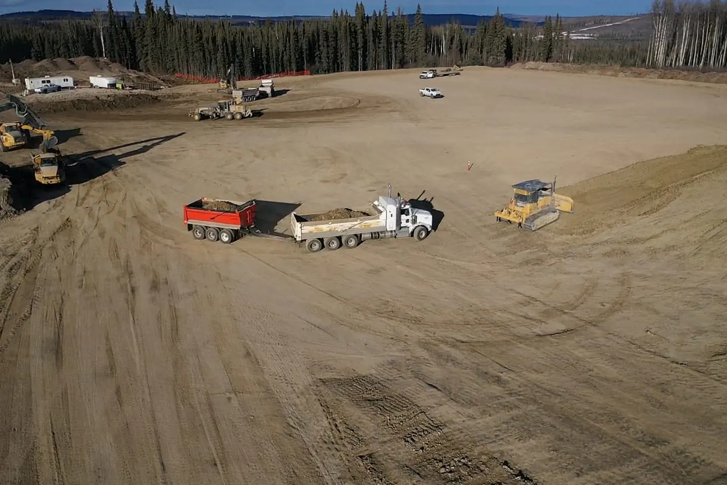 Loaded end dump unit on a pad beside a dozer spreading fill