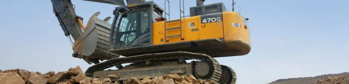 Tracked excavator with a bucket raised over broken rock