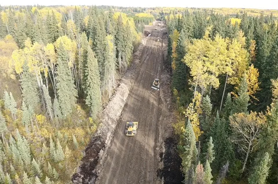 Aerial view of two dozers grading a freshly cut corridor through autumn forest