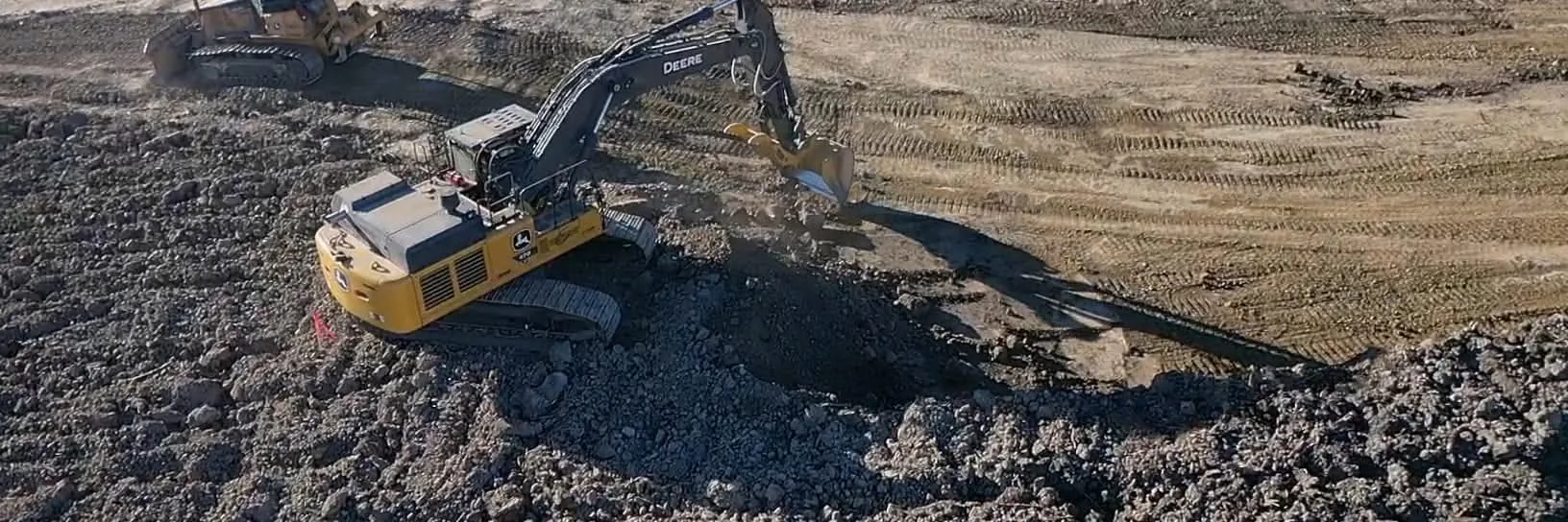 Excavator and dozer cutting subgrade on a pad build