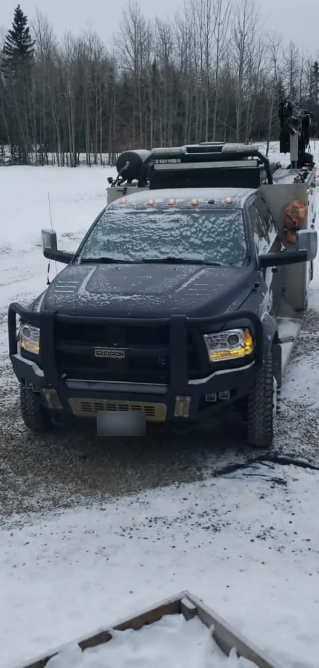Service truck with a picker and winch parked on a snow-covered pad
