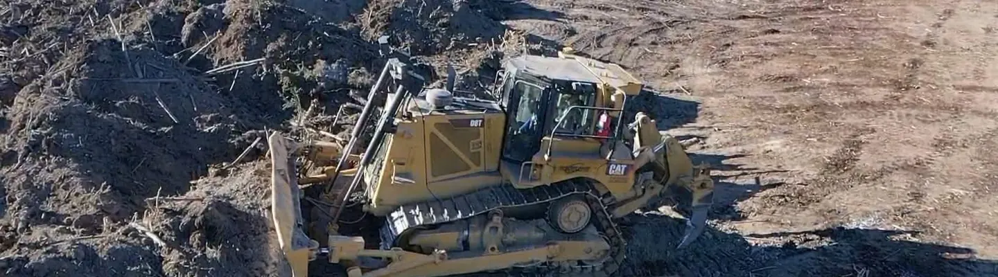 Cat D8T dozer piling brush and debris along the edge of a cleared block