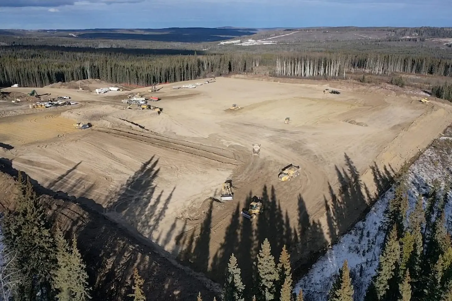 Aerial view of a large graded pad cut into a forested hillside