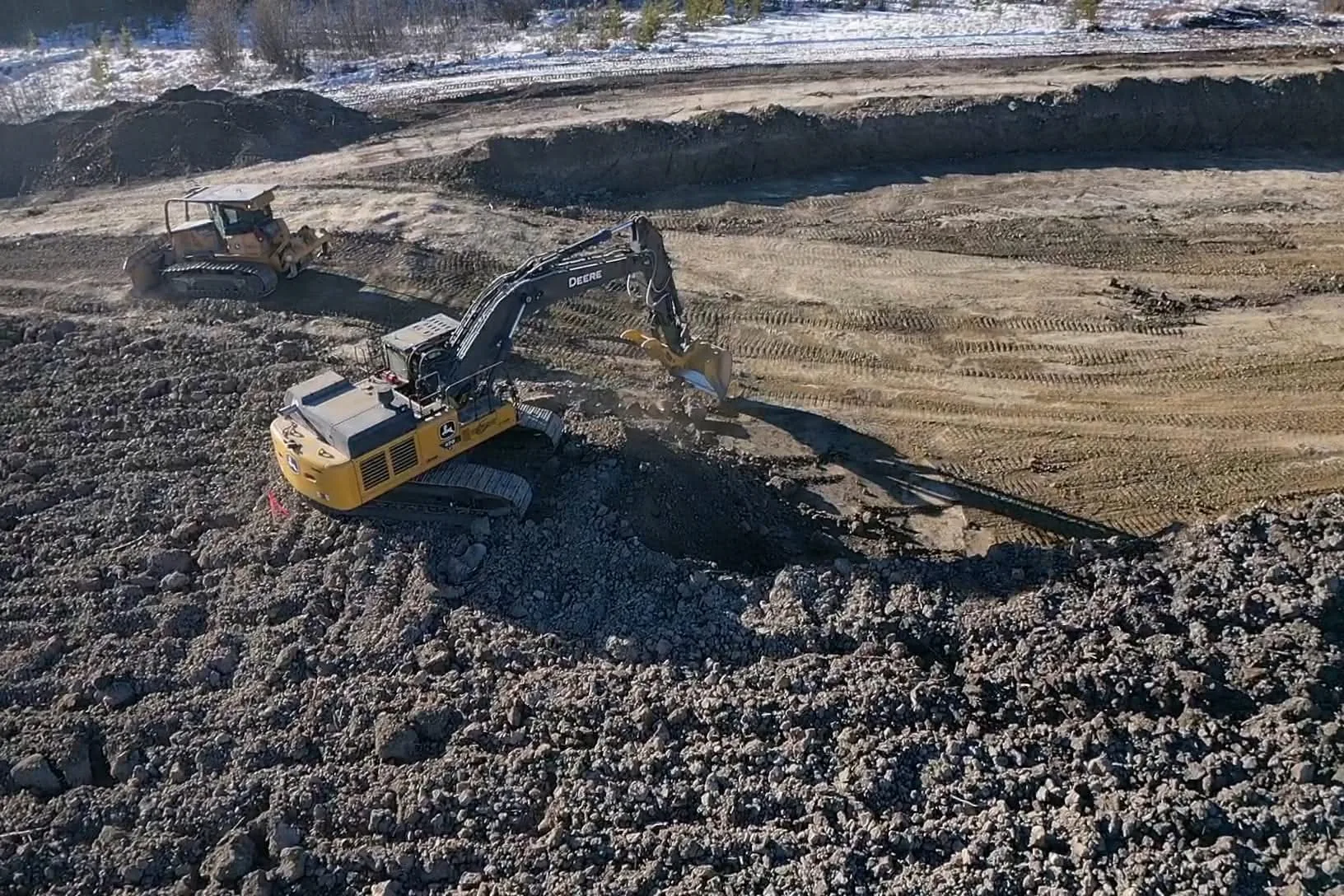 Excavator and dozer cutting subgrade on a pad build