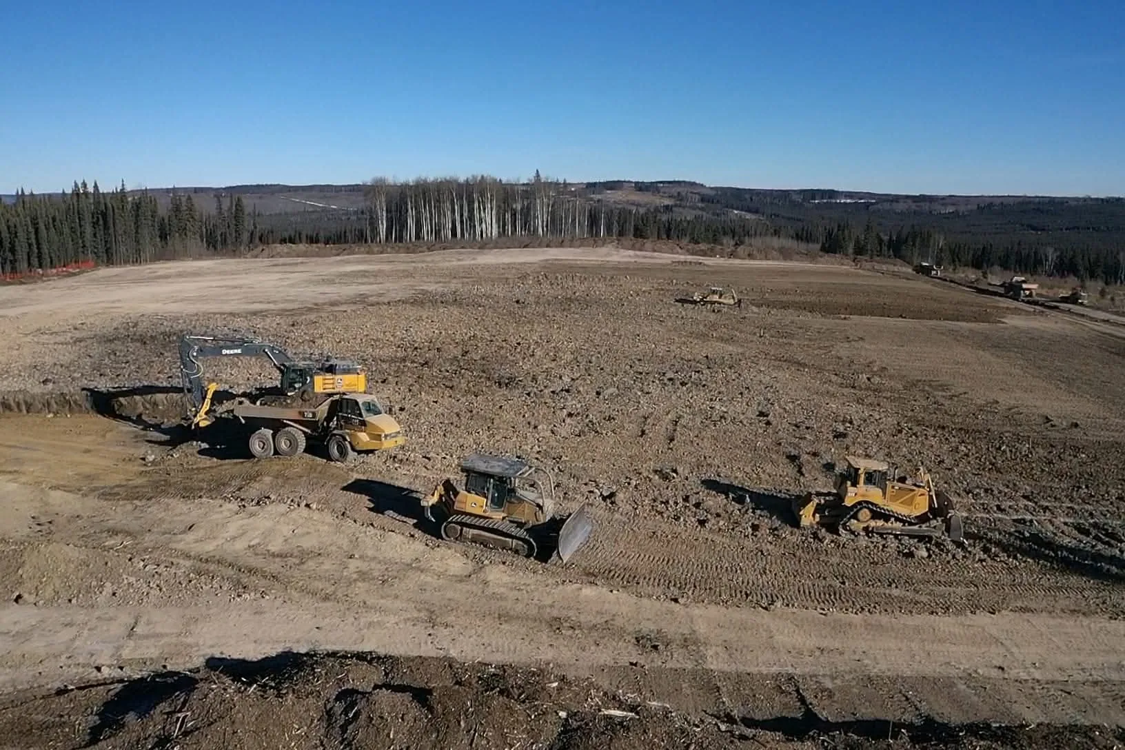 Excavator, rock truck and two dozers working together on a pad build