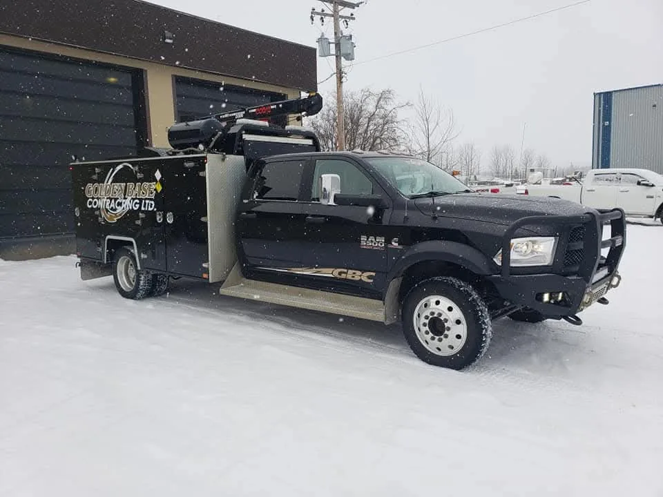 Service truck with a crane and enclosed tool body parked outside a shop in falling snow