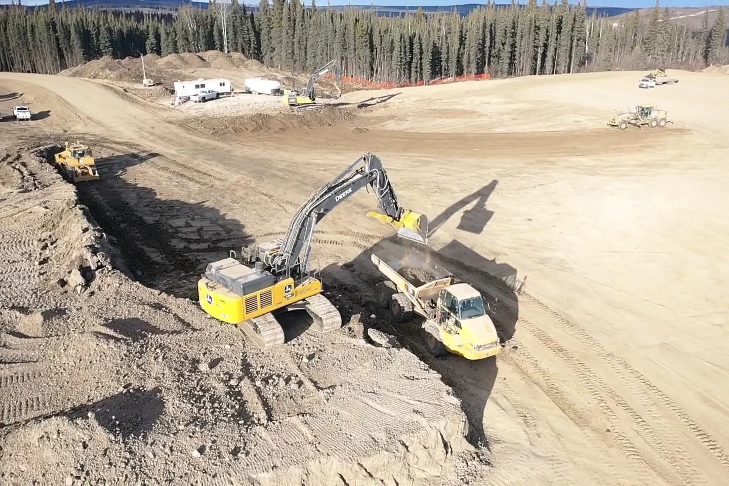 Tracked excavator loading an articulated rock truck from a cut face