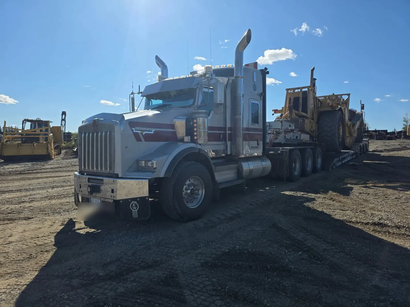 Kenworth tractor loaded with a motor scraper on a double drop low bed trailer