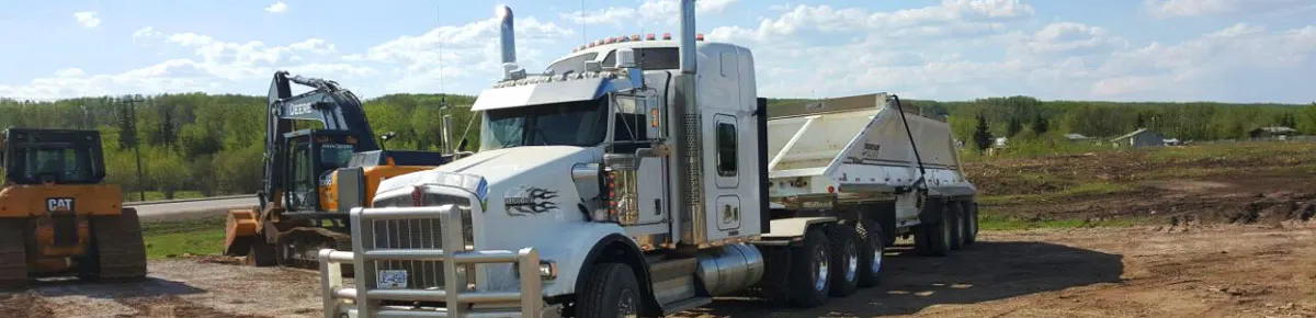 Kenworth tractor with a belly dump trailer parked beside a tracked excavator