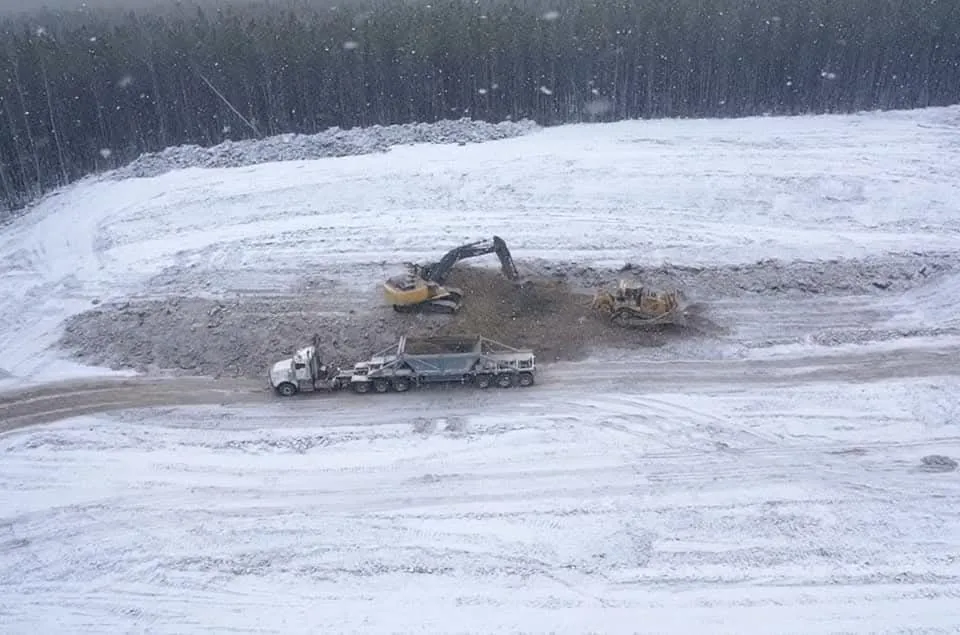 Excavator, dozer and end dump working a snow-covered pad