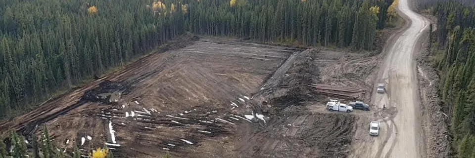 Aerial view of a cleared pad with salvaged timber decked beside a gravel access road