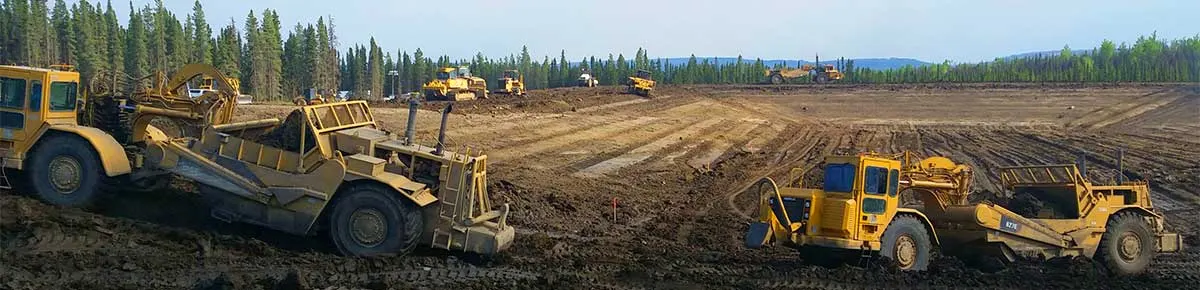 Scrapers and dozers moving earth on a cleared lease site